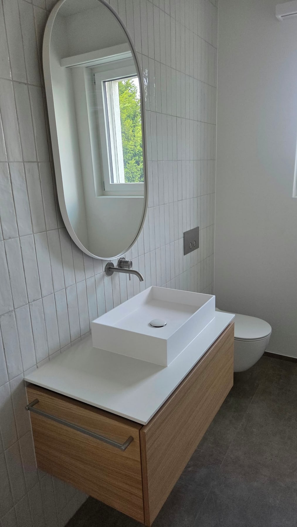 Waschplatz mit ovalem Spiegel, Wandarmatur und Holzunterschrank